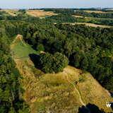 Widok z drona na Kopiec Kościuszki i pola pod Racławicami - wzniesienie porośnięte trawą, wokół dużo drzew.