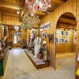 Wystawa strojów, obrazów i innych góralskich przedmiotów w drewnianym wnętrzu muzeum.
