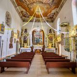 Wnętrze kościoła z polichromowanym stropem, dwa rzędy drewnianych ławek, na wprost ołtarz główny. Na ścianach obrazy i ołtarzyki.