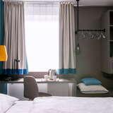 Pokój w hotelu, łózko, biurko, szafki, lampy.
