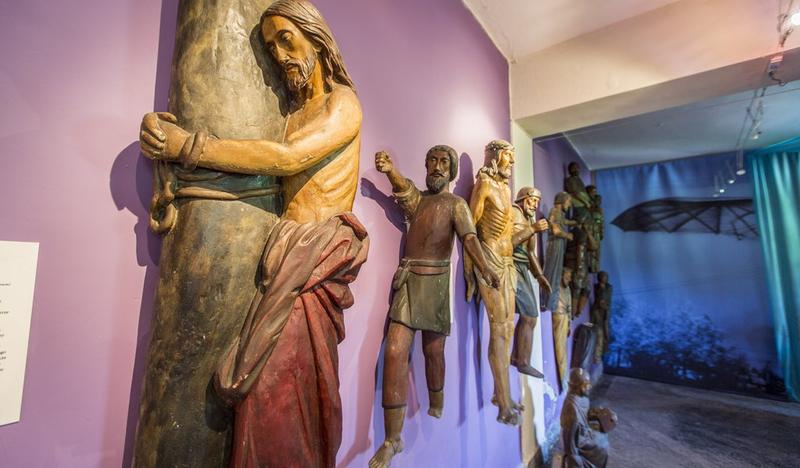 Widok na rzeźby Jezusa i innych świętych przytwierdzone do ściany w muzeum