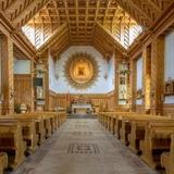 Wnętrze nawy kościelnej w drewnie, pięknie zdobione w stylu góralskim. Na środku ołtarz główny, po bokach rzeźbione ławy.