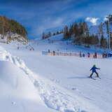 Narciarz na stacji narciarskiej CzorsztynSki zjeżdżający na nartach ze stoku. Ładna pogoda, bezchmurne niebo.