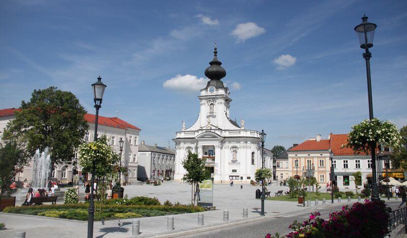 Główny plac w Wadowicach z widoczną bazyliką o białej fasadzie z wieżą.