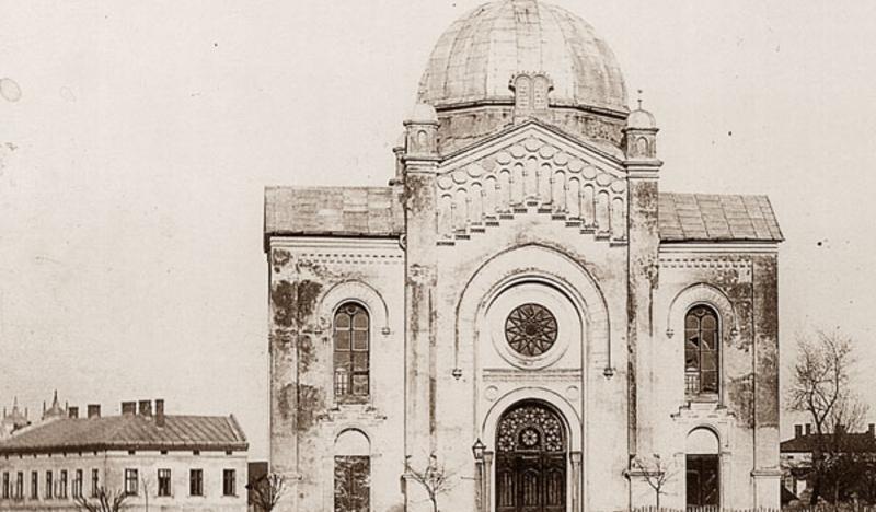 Czarno-białe zdjęcie przedstawiające wysoki budynek synagogi, zwieńczony kopułą.