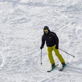 Osoba ubrana w strój narciarski zjeżdża ze stoku na nartach