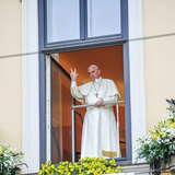 Stojący w otwartym papieskim oknie papież Franciszek w białej szacie.