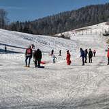 Klika osób ubranych w stroje narciarskie zimą obok Gubałówki