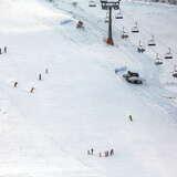 Widok na stację narciarską RyterSki, kilku narciarzy szusujących po stoku, w tle widok na wyciąg krzesełkowy.