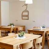 Nowoczesne, jasne wnętrze, drewniane prostokątne stoły z krzesłami z oparciami.