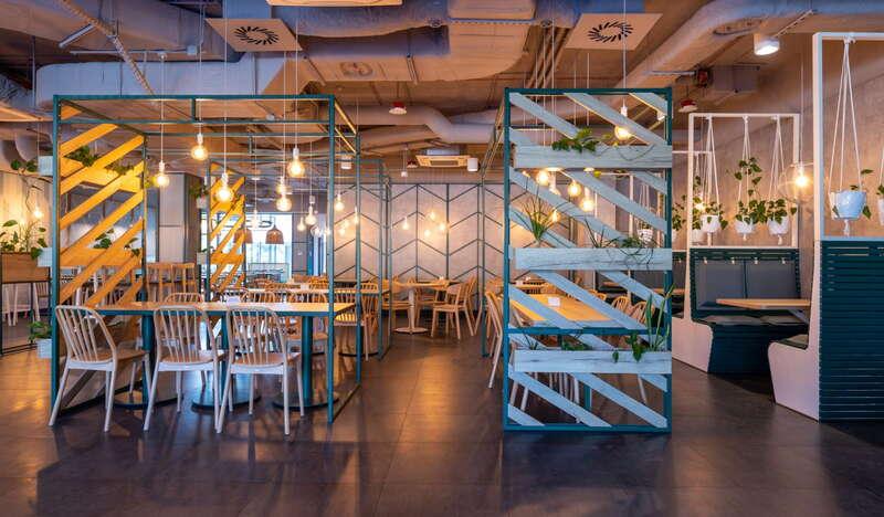 Wnętrze restauracji, stoliki z krzesłami, żółte lampy.