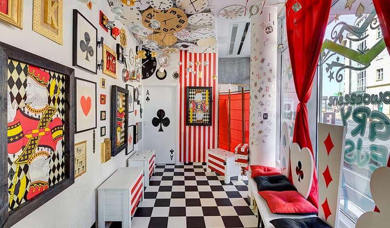 Kolorowe pomieszczenie, podłoga w czarno-białą szachownicę, czarne i czerwone elementy do gry w karty na ścianach jako dekoracje