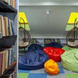Wnętrze biblioteki, regały z książkami, kolorowe pufy, wiszące fotele
