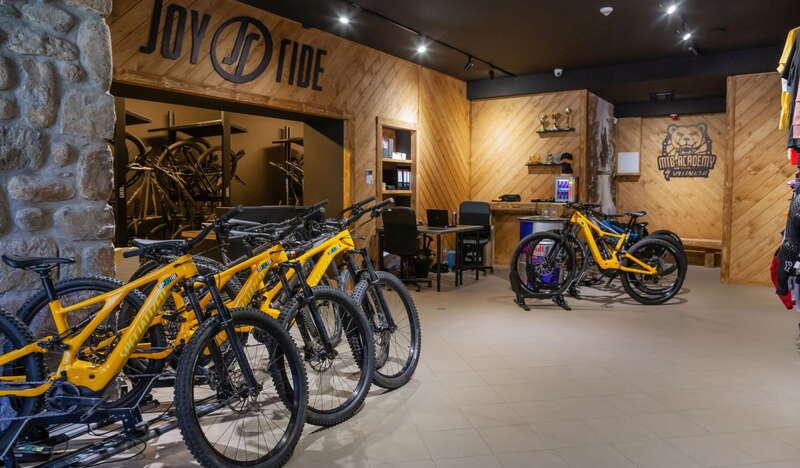 Wnętrze wypożyczalni, kilka żółtych rowerów MTB ustawionych obok siebie.