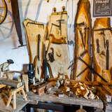 Drewniane narzędzia oraz kawałki drewna na stołach w chacie w dobczyckim Skansenie PTTK.