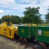 Żółta niska lokomotywa z dwoma zielonymi za nią kontenerami z napisem 