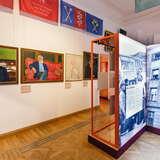 Po lewej wiszące obrazy na ścianie z wizerunkiem Wisławy Szymborskiej, księdza Bonieckiego i innych ważnych osobistości. Po prawej tablica informacyjna. Po lewej na ścianie wysoko wiszą proporczyki z nazwą Uniwersytetu Jagiellońskiego.