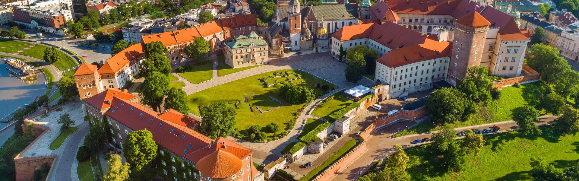 Das Königsschloss Wawel aus der Vogelperspektive. Der Innenhof des Schlosses ist mit Gras bewachsen und von Sträuchern umgeben. Gebäude im Hintergrund.