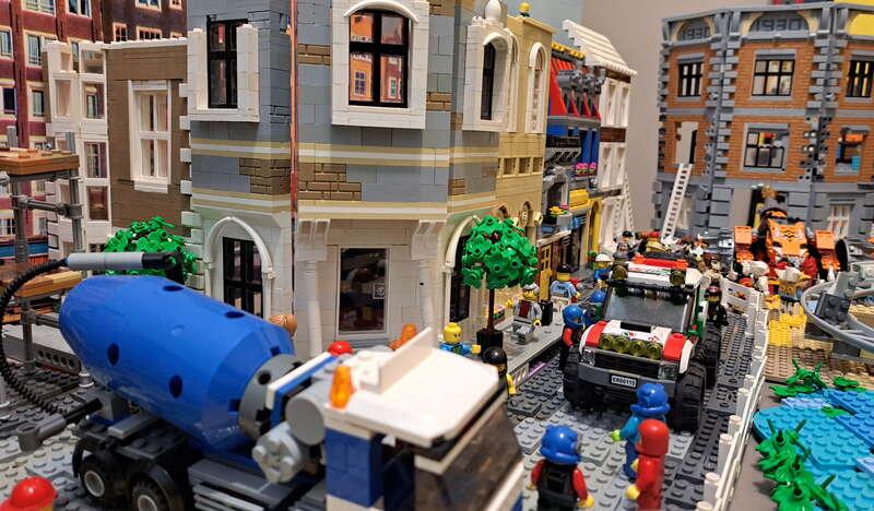 zbliżenie na betoniarkę zbudowaną z klocków LEGO, w tyle inny pojazd i zabudowania