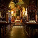 Bogato zdobione wnętrze kościoła, w centralnym punkcie pozłacany ołtarz, po bokach dwa ołtarze boczne, drewniane ławy, centralnie wisi zdobny żyrandol.